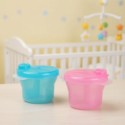 Boite lait en poudre sans bpa rose et bleu sur table dans chambre bébé