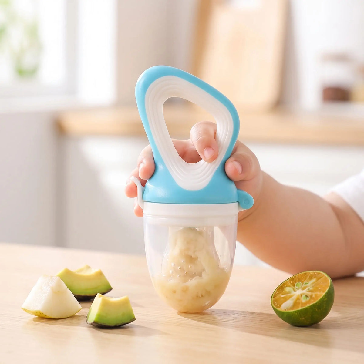 Grignoteuse-bébé-en-silicone-avec-fruit-sur-table-cuisine-main-bébé